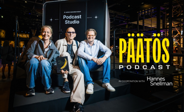 Three people sit smiling on steps outside a Podcast Studio booth. The word PÄÄTÖS PODCAST is prominent, along with in cooperation with Hannes Snellman. The setting appears modern with bright lighting.